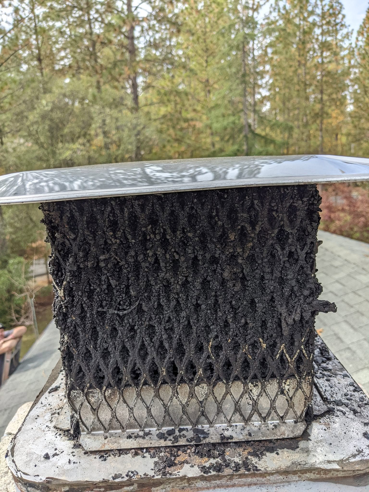 Creosote accumulation on a chimney cap before cleaning