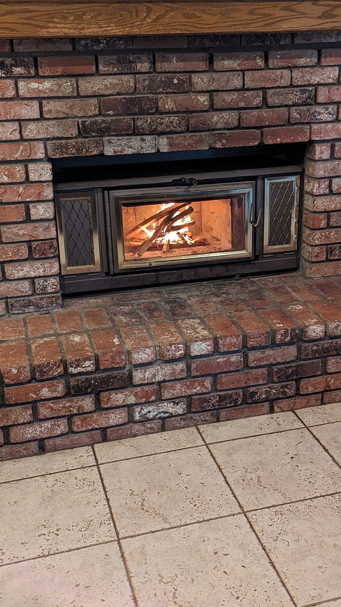 A wood-burning insert set into a brick fireplace